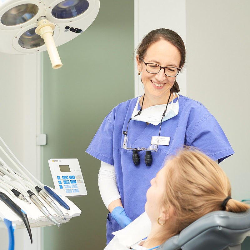 Impressionen: Eine Ärztin lächelt eine Patientin an, die auf dem Behandlungsstuhl sitzt